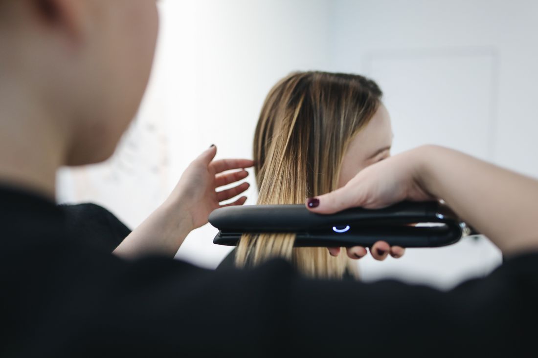 Close-up of a stylist straightening and finishing smooth, glossy hair