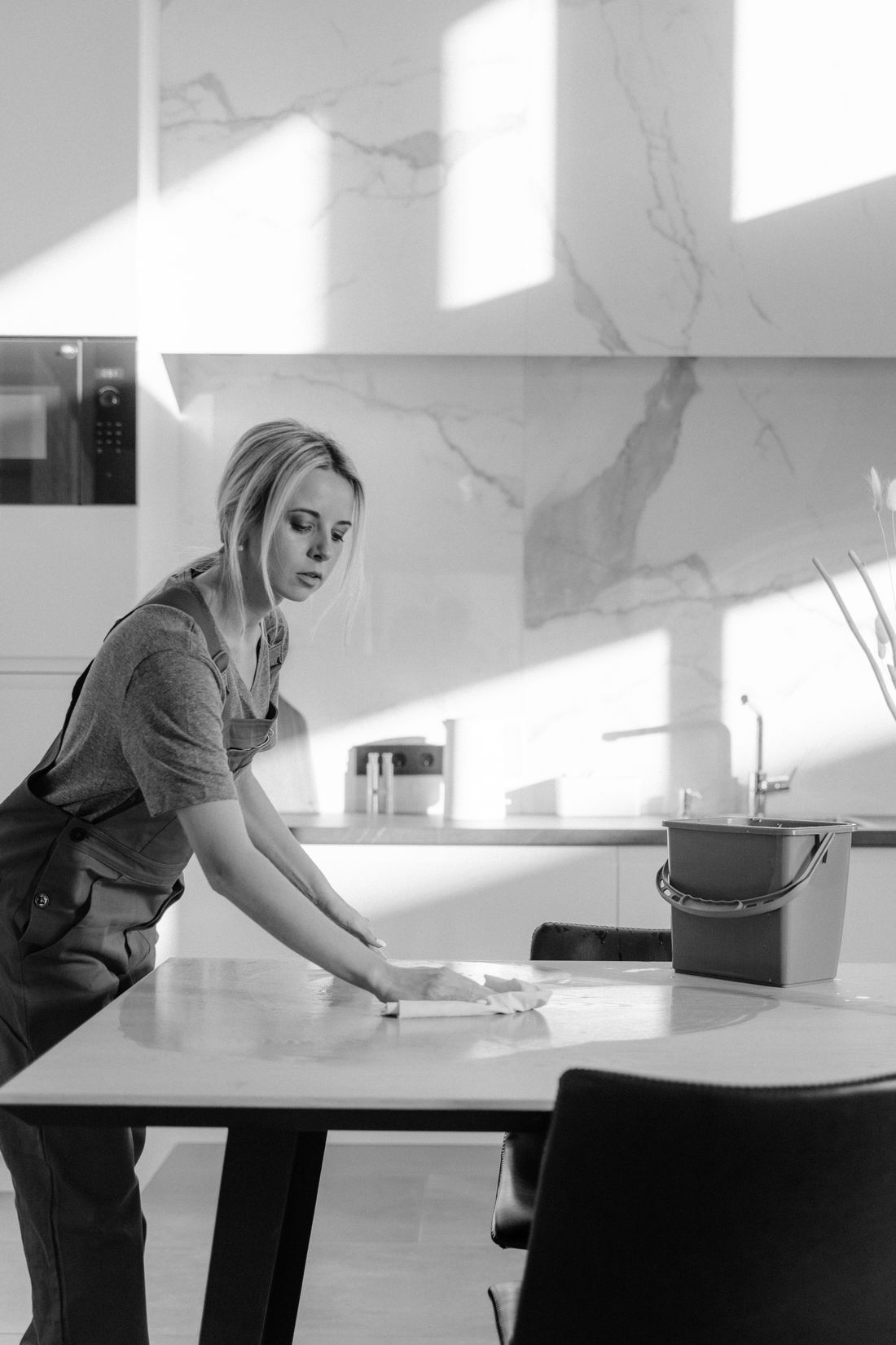 Cleaner sanitising the worktops in a bright, modern kitchen